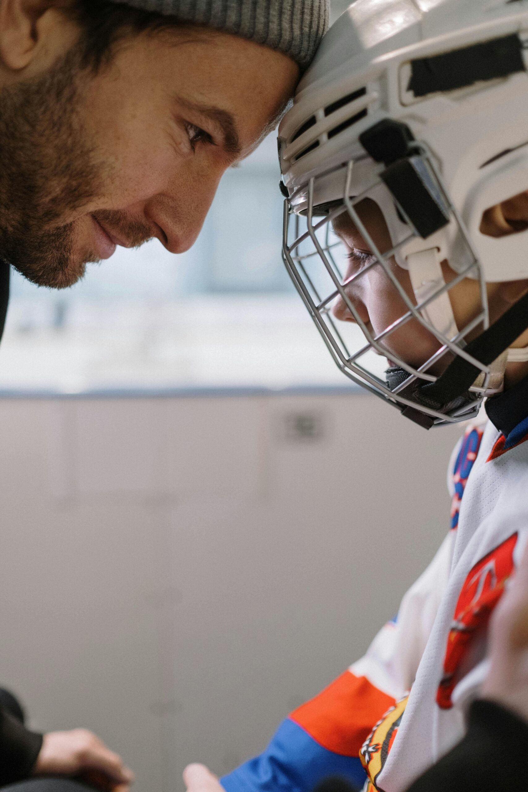 A father encourages his young son before an ice hockey match, showing support and motivation.