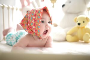Cheerful baby with colorful scarf and toys — exploring mobility and teething.