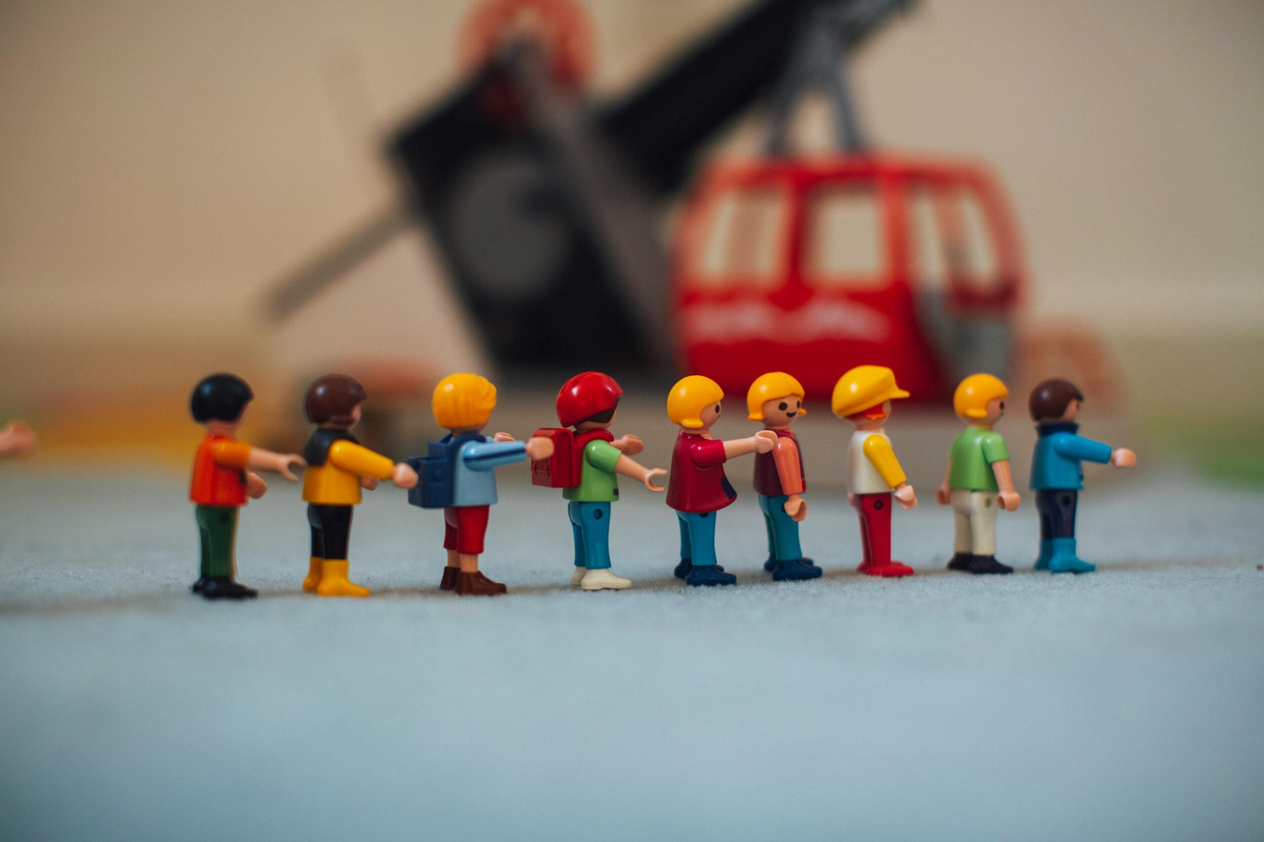 Miniature plastic figures arranged in front of a toy helicopter, illustrating a small world play scene for imaginative learning.