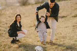 Family enjoying outdoor soccer together, showing joyful connection and bonding in parenting.