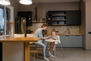 A mother tenderly feeds her baby in a stylish kitchen scene, capturing warmth and family bonding.
