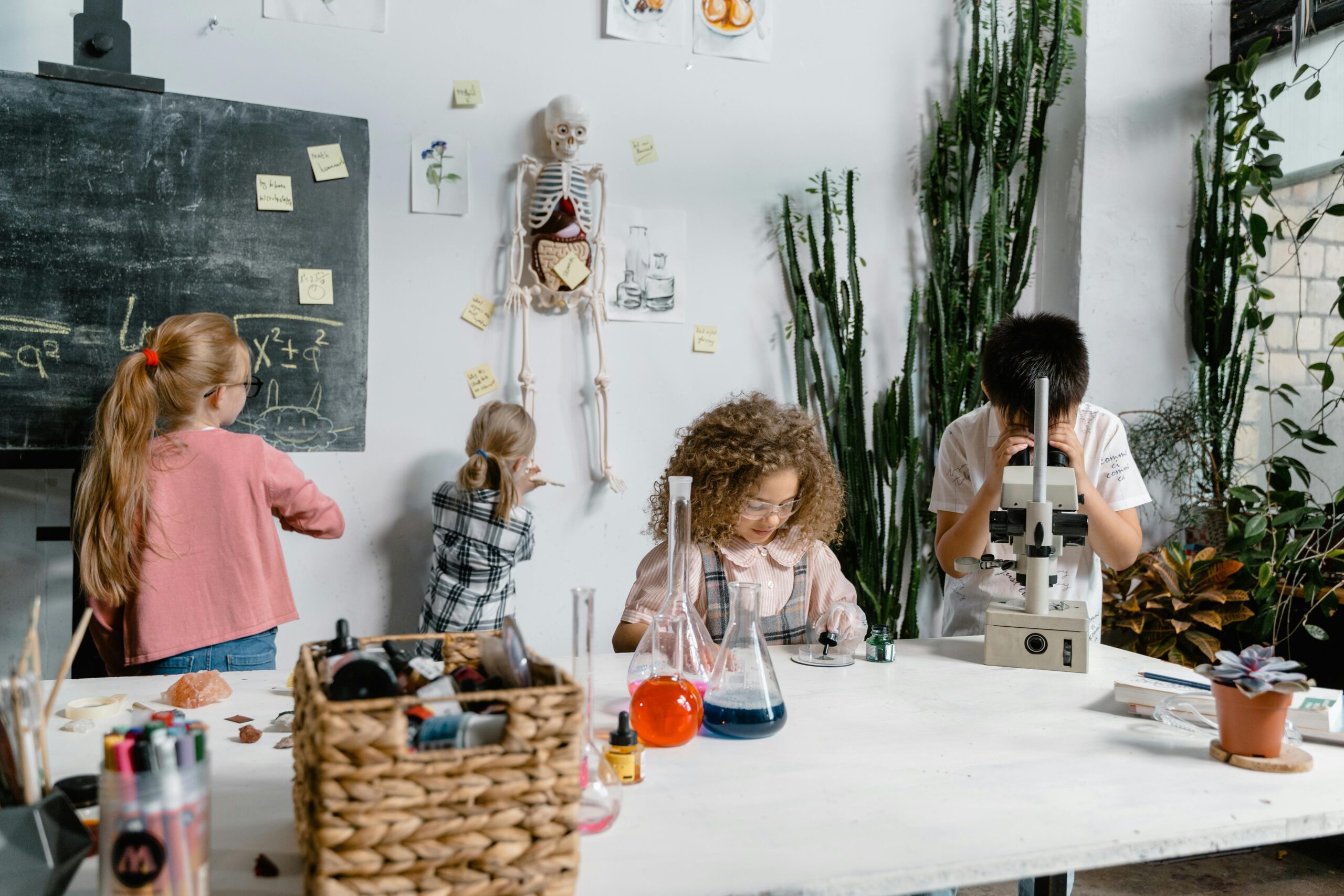 Curious children conducting science experiments in a classroom with flasks and a microscope.